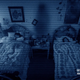 Two characters from Paranormal Activity 3, sleeping while a shadow stands between them in their room.